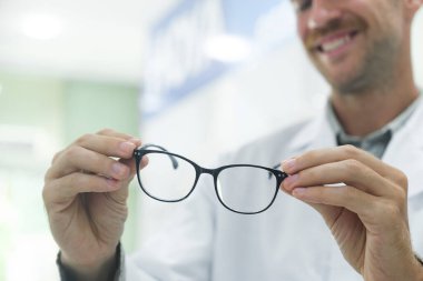 Profesyonel gözlükçü, müşterilerine optik mağazasında muayeneyi bitirdikten sonra yeni gözlüğü için doğru çerçeveyi seçmelerini ve karar vermelerini öneriyor..