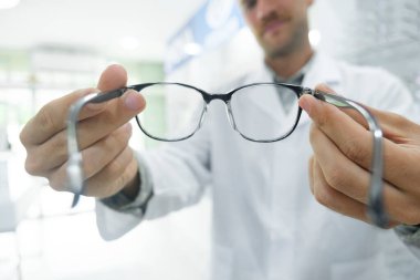 Profesyonel gözlükçü, müşterilerine optik mağazasında muayeneyi bitirdikten sonra yeni gözlüğü için doğru çerçeveyi seçmelerini ve karar vermelerini öneriyor..