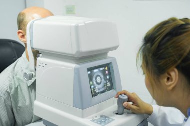 Gözlükçü dolabında oturan zeki yakışıklı adam yeni gözlük gözlüğü için özel ekipman makinesiyle görme, inceleme ve test yapıyor..