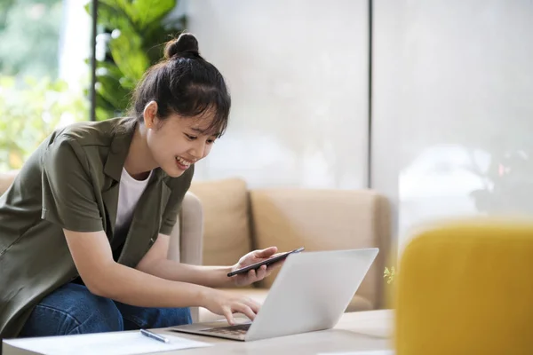 年轻的亚洲女商人用手机与客户取得联系 在办公室里努力工作 使用笔记本电脑数据图表 计划改进 分析和制定业务增长战略 业务概念 — 图库照片