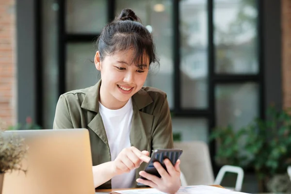 年轻的亚洲女商人用手机与客户取得联系 在办公室里努力工作 使用笔记本电脑数据图表 计划改进 分析和制定业务增长战略 业务概念 — 图库照片