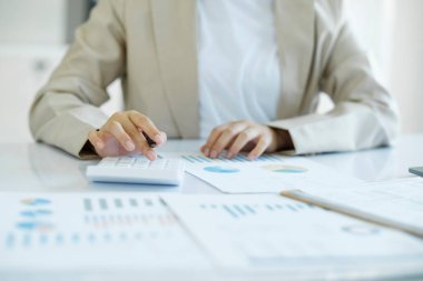 Accountant is working on her desk about budget of the company. Closeup of businesswoman hand is analyzing and calculating the invesment online markting.