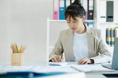 Accountant is working on her desk about budget of the company. Businesswoman hand is analyzing and calculating the invesment online markting.