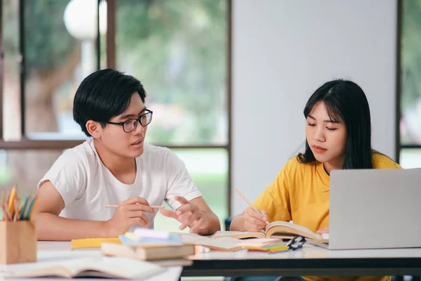 亚洲的年轻大学生正在准备考试 有与朋友合著的家教书籍 他们是试图互相帮助的同学 他们在校园里做了好几个小时的家教 — 图库照片