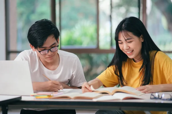 若いアジアの大学生は試験のために勉強している 友人との家庭教師の本があります 彼らはお互いを助けようとするクラスメートです 彼らはキャンパスで何時間も指導してきました — ストック写真
