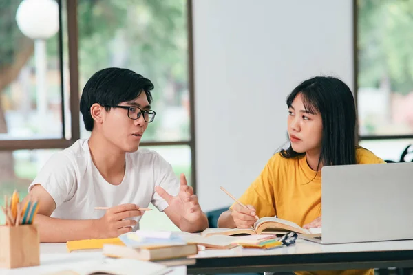 亚洲的年轻大学生正在准备考试 有与朋友合著的家教书籍 他们是试图互相帮助的同学 他们在校园里做了好几个小时的家教 — 图库照片