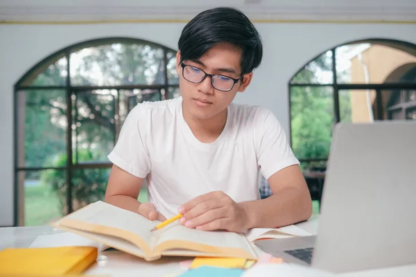 若いアジアの大学生は試験のための本を読んでいます 大学生の自己学習と大学の学習室でオンライン学習 — ストック写真