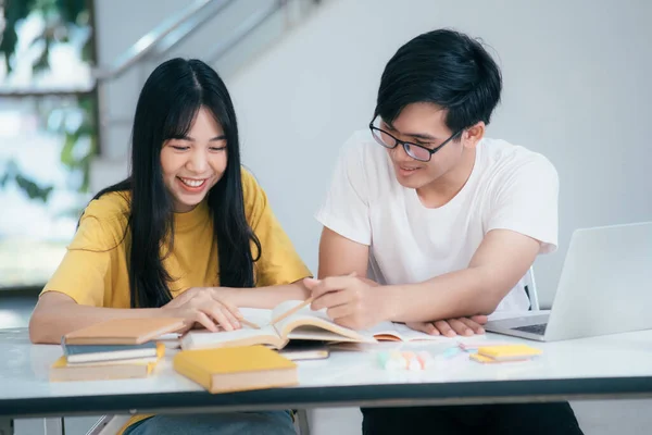 若いアジアの大学生は試験のために勉強している 友人との家庭教師の本があります 彼らはお互いを助けようとするクラスメートです 彼らはキャンパスで何時間も指導してきました — ストック写真