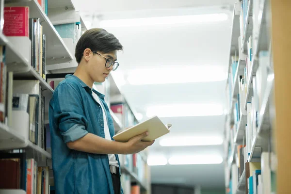 学術研究や学校の仕事を勉強するために図書館で読むために バックパックの立って 読書や選択本を持つカジュアルな服装の若い男性学生 教育の概念 — ストック写真