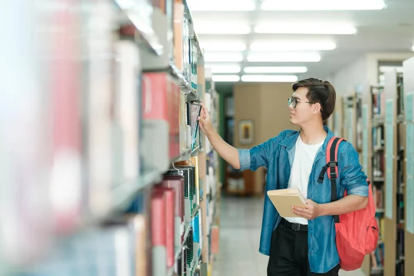 Young Male Student Casual Outfit Backpack Standing Reading Choosing Books — Stock Photo, Image
