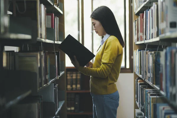 身着休闲装的女大学生 为学习 学术研究 学校工作 项目或考试选择在图书馆看书或看书 图书馆概念 — 图库照片