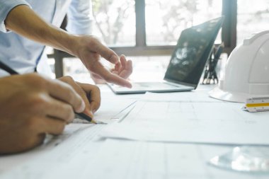 Birlikte çalışan iki mühendis, geliştirici ya da mimarın yakın plan çekimleri, inşaat projesinin grafik tasarımı, kağıtlar ve diğer ekipmanlarla birlikte çalışma masasında gelişim için işaret etmek ve tartışmak. Mühendis ve Takım Çalışması Konsepti.