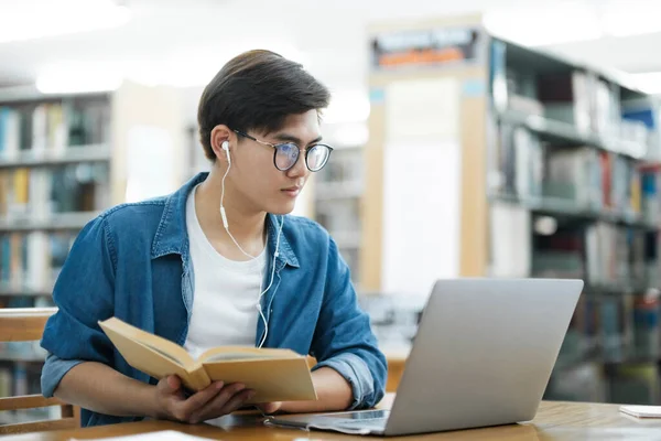 헤드폰을 착용하고 책상에 연구나 과제를 노트북을 사용하여 공부하고 대학생 — 스톡 사진