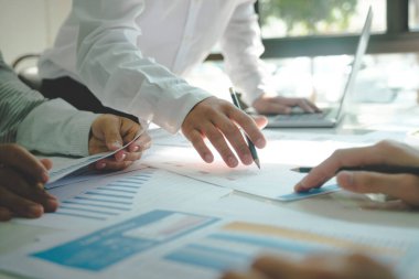 İş yerinde birlikte çalışan iş adamlarının yakın çekimleri, stratejiler, planlar, analitik ilerleme ve şirketin mali istatistikleri hakkında tartışmalar ve masadaki grafik belgelerine kalemlerle işaret etmek. İş ve Takım Çalışması konsepti.