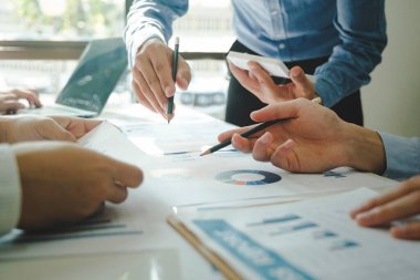 İş yerinde birlikte çalışan iş adamlarının yakın çekimleri, stratejiler, planlar, analitik ilerleme ve finansal istatistikler hakkında tartışmalar ve masadaki grafik belgelerine dizüstü bilgisayar ve pano ile işaret etmek