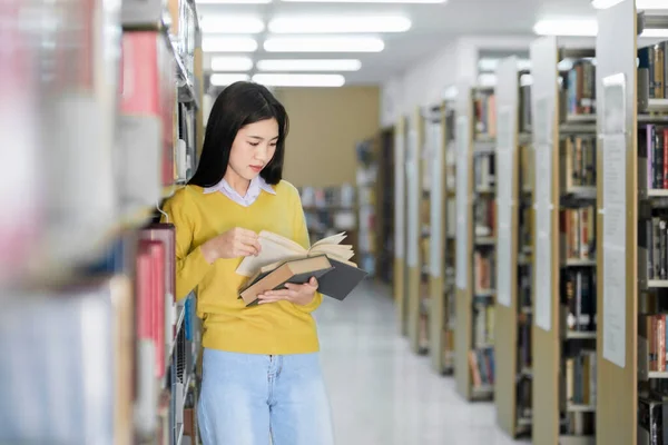 身着休闲装的女大学生 为学习 学术研究 学校工作 项目或考试选择在图书馆看书或看书 — 图库照片
