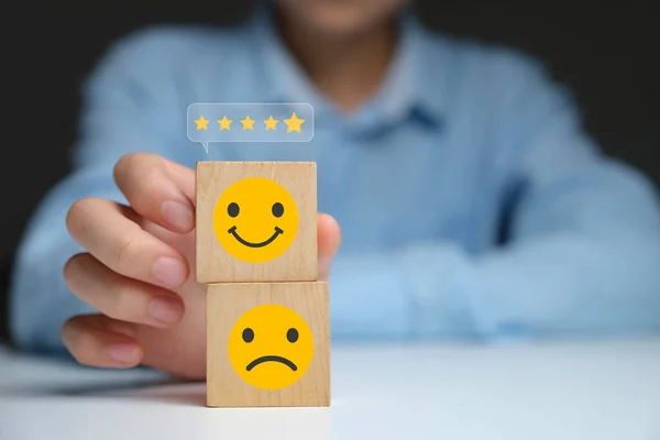 顧客満足の概念 閉じる顧客の手は 木材キューブ上の笑顔の顔とぼやけた悲しい顔のアイコンを選択します サービス評価 満足コンセプト — ストック写真