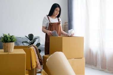 Yeni bir eve taşınırken ya da yeni bir daireye taşınırken kutuları paketleyen ya da boşaltan mutlu bekar bir kadın. Yeni duygular başlar. Yalnız yaşamak. Modern kadın insanlar evlerine taşınıyor.