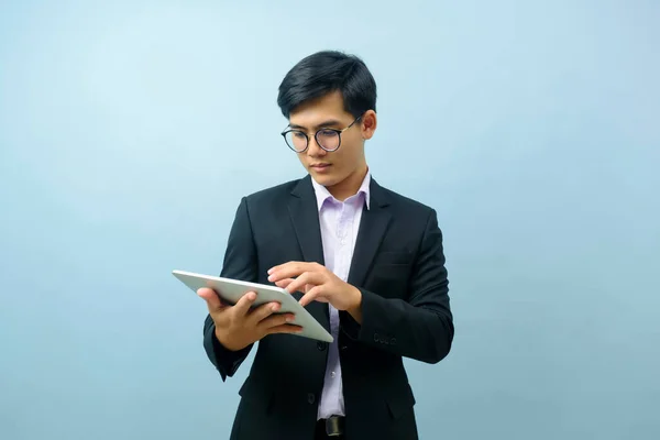 年轻聪明的亚洲商人的肖像 戴着眼镜站着 微笑着 用平板电脑工作或与浅蓝色孤立的背景进行交流 联系概念 — 图库照片