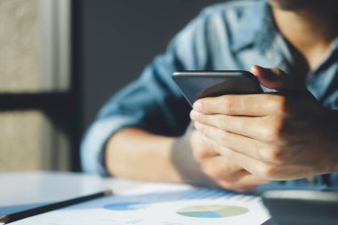 İş adamlarına yakın plan, çevrimiçi grafik ve diyagramları olan cep telefonlarına bakarak yatırım verilerini analiz ediyor. Mali rapor sunumunu kontrol ediyor..