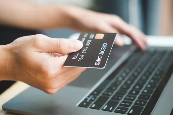 若いビジネスマンの手はクレジットカードを保持し 自宅でノートパソコンを使用して オンラインショッピングや請求書を支払う 支払い方法 — ストック写真