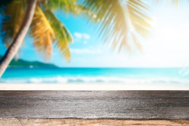 Deniz manzaralı ahşap masa, sakin deniz ve tropik plaj arka planında gökyüzü. Ürün görüntüleme kurgunuz için boş masa hazır. Yaz tatili konsepti.
