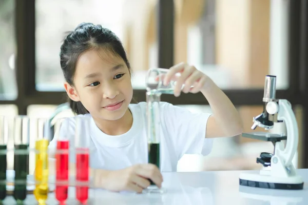 stock image Schoolgirl is dropping a the liquid substance into the test tube with a long glass pipette in the scientific chemical laboratory.