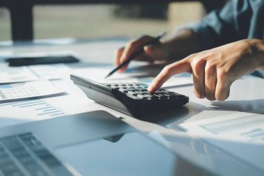 Bir müşteriyle vergileri sayıp tartışırken hesap makinesi ve dizüstü bilgisayar kullanan iş adamı muhasebeci. İş denetimi ve finans kavramları