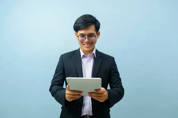 年轻聪明的亚洲商人的肖像 戴着眼镜站着 微笑着 用平板电脑工作或与浅蓝色孤立的背景进行交流 联系概念 — 图库照片