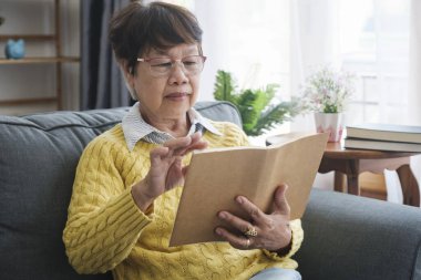 Yaşlı Asyalı kadın evde koltukta oturmuş kitap okuyor, gözlük takıyor. Emekli erkek hafta sonları roman ya da iş edebiyatı okumaktan zevk alıyor. Emeklilik Konsepti
