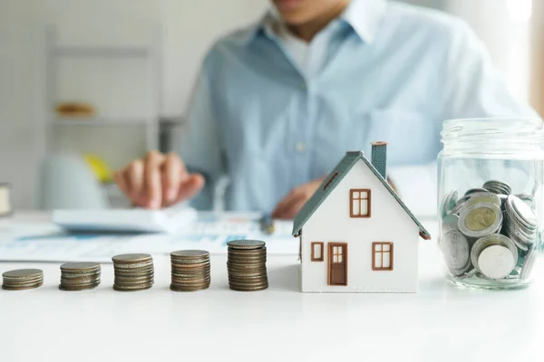 Saving investment home with loan finance money business concept. Investment banking finance for residential real estate business. Stack coins with model house for investment loans. Cash for taxes.
