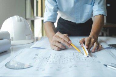 Bir mimar ve mühendisin elleri mimari planı işaret ediyor. Her şeyin yolunda gittiğinden emin olmak için bir koordinasyon toplantıları var..