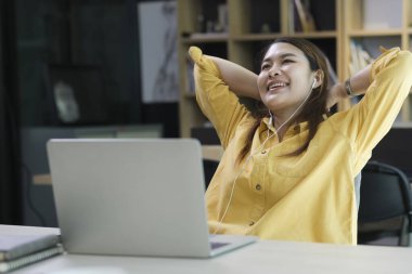 Yapılan işten memnun. Ofisinde çalışırken dizüstü bilgisayarda çalışan mutlu genç bir kadın.