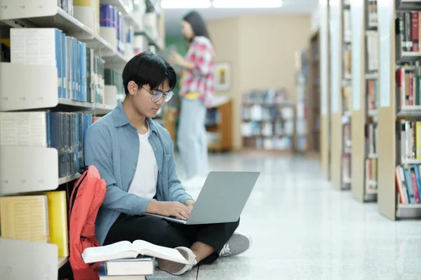 大学図書館 スマートアジアの大学生は ノートパソコンを使用しています 論文のためのメモを書きます エッセイ クラスの割り当てのための研究 集中的に学ぶ学生 大学の試験のために勉強 — ストック写真