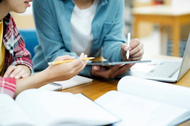 Genç öğrenci kampüsü arkadaşa yetişip öğrenmede yardımcı olur. Üniversite öğrencileri kütüphanedeki görevleriyle işbirliği içinde. Masada oturup kitap okuyan bir grup genç. Eğitim ve