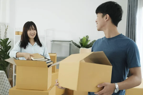 Young couple moving in new home.Couple is having fun with cardboard boxes in new house at moving day.