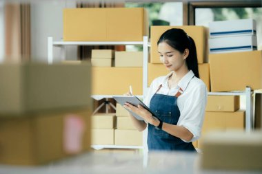 Mutlu girişimciler siparişleri kontrol etmek için tablet kullanır ve müşterilere mal teslimatı için hisse senetlerini kontrol ederler. Küçük işletme sahibi ve çevrimiçi iş kavramlarında başarı.