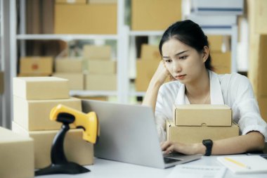 Asyalı girişimci çevrimiçi işletme sahibi iş problemleri konusunda yorgun ve stresli ve ilk ürün parasının kaybedilmesi, merkez ofisteki bilgisayardan çevrimiçi siparişi kontrol ettiğinde satılamaz.