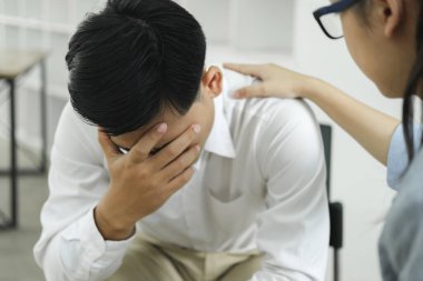 Psikiyatrist ya da danışman hastaları teselli etmek ve cesaretlendirmek için elini tutuyor. Genç Asyalı kadın psikolog erkek hastanın bileğini tutuyor. Önünde oturuyor ve sorunlarını paylaşıyor..