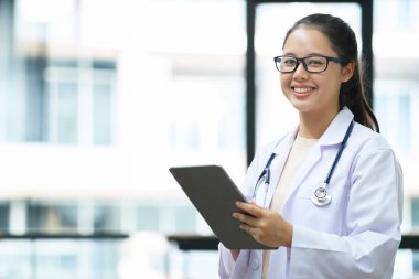 Dijital tablet kullanan bir doktorun görüntüsü. Klinikte dijital tablet kullanan doktorların ellerini kapatın. İşçi ceketli ve steteskoplu doktorun dijital tablet tutuşu. Doktor üzerinde çalışıyor.