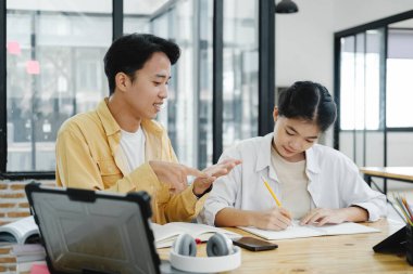 Öğrenme, eğitim ve okul konsepti. Genç bir kadın ve erkek sınava ya da sınava çalışıyor. Arkadaşlarla ders kitapları. Genç öğrenci kampüsü arkadaşa yetişip öğrenmede yardımcı oluyor.