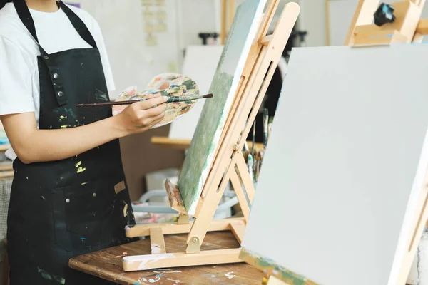 年轻的女画家在工作室的画布上画或画她的画 喜欢艺术和绘画的少女正在花些时间在画布上创作她的水彩画 — 图库照片
