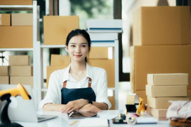 Genç iş kadını dükkanında online e-ticaret alışverişi yapıyor. Genç kadın satıcı müşteriye teslim etmek için bir paket ürün hazırla. Online satış, e-ticaret.