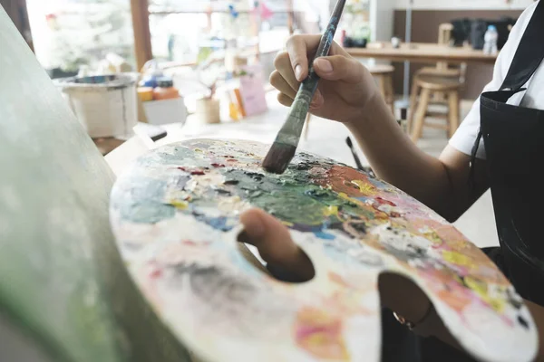 年轻的女画家在工作室的画布上画或画她的画 喜欢艺术和绘画的少女正在花些时间在画布上创作她的水彩画 — 图库照片