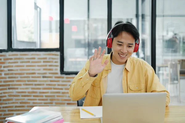 Video call online meeting. Young man waving to his colleague and explaining and discuss his opinions during the online meeting. Online learning, online business concept.