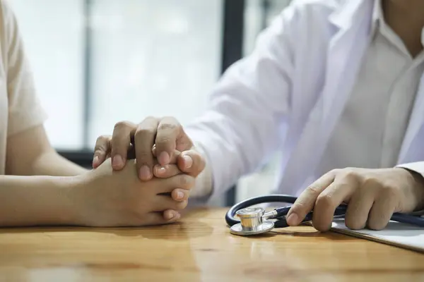 Kind doctor offering a loving gesture to a sick person during a health crisis. Support, trust and hospital care with a doctor and patient holding hands, sharing bad news of a cancer diagnosis.