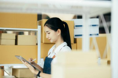 Mutlu girişimciler siparişleri kontrol etmek için tablet kullanır ve müşterilere mal teslimatı için hisse senetlerini kontrol ederler. Küçük işletme sahibi ve çevrimiçi iş kavramlarında başarı.