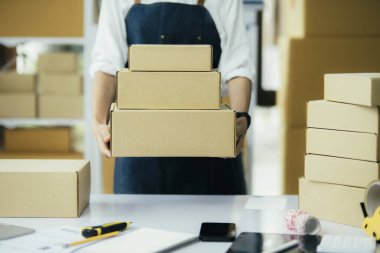 Genç iş kadını dükkanında online e-ticaret alışverişi yapıyor. Genç kadın satıcı müşteriye teslim etmek için bir paket ürün hazırla. Online satış, e-ticaret.