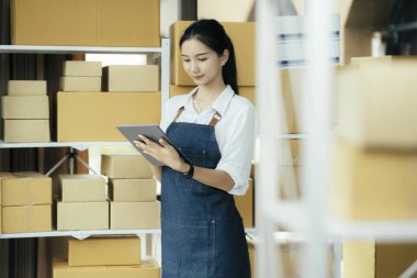 Mutlu girişimciler siparişleri kontrol etmek için tablet kullanır ve müşterilere mal teslimatı için hisse senetlerini kontrol ederler. Küçük işletme sahibi ve çevrimiçi iş kavramlarında başarı.