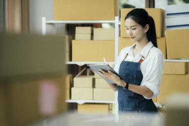 Mutlu girişimciler siparişleri kontrol etmek için tablet kullanır ve müşterilere mal teslimatı için hisse senetlerini kontrol ederler. Küçük işletme sahibi ve çevrimiçi iş kavramlarında başarı.